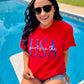 A person wearing a red t-shirt with the text 'PARTY' and 'USA' embroidered on it, sitting by a pool.