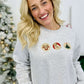 Person wearing a Ash sweatshirt with Christmas-themed cookies in front of a decorated Christmas tree.