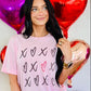A person wearing a pink t-shirt with heart and 'XOXO' text design, surrounded by balloons and decorations with a Valentine's Day theme.