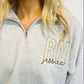 A woman wearing a gray sweatshirt with 'RN' embroidered on the front.