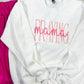 White embroidered sweatshirt with the text 'PRAYING Mama' and a graphic of a mother holding a child.