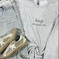 A gray sweatshirt with the text 'BOY MAMA' embroidered on the front, paired with blue jeans and white sneakers with embellishments on the sole.
