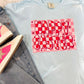 A light blue colored t-shirt with a 'Happy Easter' text and pink checkered pattern on it, displayed on a flat surface with denim jeans and a wooden object in the background.