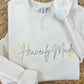 White sweatshirt with 'Heavenly Made' text on a woven surface
