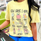 Person wearing a butter yellow t-shirt with Teacher God says I am motivational phrases and graphics in a school setting