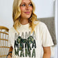 Woman wearing a white t-shirt with 'MAMA' text and camouflage bow design.