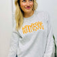 Woman wearing a gray sweatshirt with 'Tennessee' in yellow text, standing indoors.