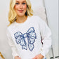 A woman wearing a white sweatshirt with a blue Chino bow graphic design on the front.