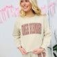 A person wearing a Tan sweatshirt and matching sweatpants set with brown puff text vinyl puff graphics.