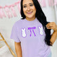 Woman wearing a purple t-shirt with graphic designs in a home setting
