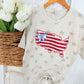 Baby onesie with USA design and bow on stars background next to white tulips in a basket.