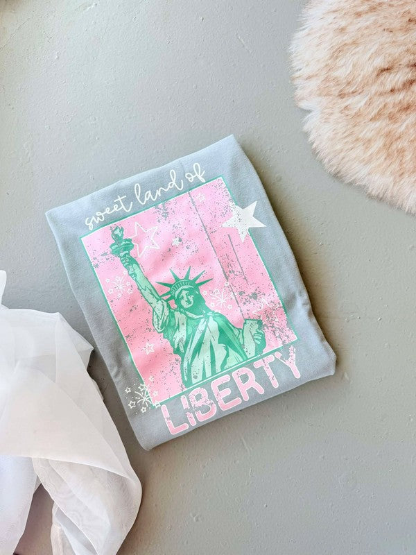 A gray t-shirt with a graphic of the Statue of Liberty in pink and green against a pink background, with the text 'LIBERTY' below the statue.