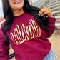 Woman wearing a maroon sweatshirt with 'Wildcats' in gold letters and denim shorts.