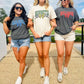 Three women wearing sports team t-shirts walking together outdoors on a sunny day.