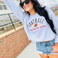 Woman wearing a gray sweatshirt with 'Football is my favorite season' text, sunglasses, and denim shorts outdoors.