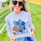 Woman wearing a 'Blue Devils' sweatshirt with a football graphic on a sports field.