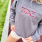 Person wearing a gray sweatshirt with 'maroon TIDE' text on a sports field background