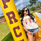 Woman posing with a large yellow and red 'PRC' inflatable tube on a grassy field.
