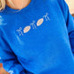 Person wearing a blue sweatshirt with white bow and football designs on a blurred background
