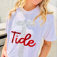 Person wearing a white t-shirt with 'Tide' printed on it, sitting outdoors.