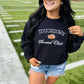 Woman wearing a black sweatshirt with 'Touchdown Social Club' text on a grassy field.