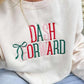 Person wearing a sweet cream sweatshirt with 'DASH FORWARD' text and a green bow embroidery in Christmas colors