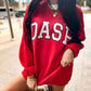 Person wearing a red sweatshirt with 'DASH'  varsity custom print on it, standing outdoors.