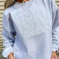Girl wearing an Ash gray sweatshirt with 'TN' embroidered on it, tonal applique same color as the sweatshirt. Standing against a neutral background.
