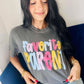 Woman wearing a gray t-shirt with 'Favorite Parent' in polka dot colorful letters, sitting on a blue couch.