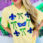 Woman wearing a yellow t-shirt with purple masks and green ribbons in front of a colorful background for Mardi Gras