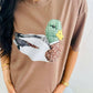 Person wearing a brown t-shirt with a viral patchwork mallard duck graphic design.