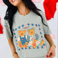 Woman wearing a light gray t-shirt with teddy bear design, standing against a colorful background.