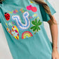 Person wearing a teal t-shirt with colorful graphics and text.
