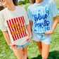 Two women walking outdoors on a grassy field wearing graphic t-shirts. The woman on the left wears a cream t-shirt with red and yellow 'PRCC Wildcat' graphics, and the woman on the right wears a light blue t-shirt with 'Blue Devils' and blue stars.
