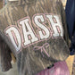 Bottomland Mossy Oak Camouflage sweatshirt with 'DASH' text and a bow on a mannequin in a store setting.