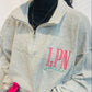 Person wearing a gray sweatshirt with 'LPN' and holding a pink water bottle.