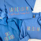 A collection of blue sweatshirts with custom embroidered text on them, like Dash Forward, displayed on a white background.
