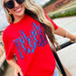 Woman wearing a red 'rebel' shirt with sunglasses outdoors.