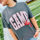 Person wearing a gray t-shirt with 'Gang' printed on it, standing on a grassy field.