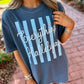 A woman wearing a slate blue graphic t-shirt with light blue vertical stripes and white cursive text reading 'Everything Hallelujah' in an outdoor setting on a brick pathway.