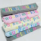 Stack of rolled-up shirts with colorful embroidery shop names on a white background