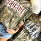 Two people wearing Real Tree camouflage t-shirts with 'Georgia' and 'Dallas' text.