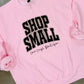 Pink sweatshirt with Leopard 'Shop Small' text on a concrete surface