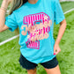 Woman wearing a blue t-shirt with a pink and white design on a grassy field
