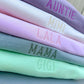 Stack of colorful fabric swatches with embroidered text on a neutral background