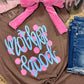 Brown t-shirt with 'Mother Hood' text and pink polka dots, paired with denim shorts and a pink bow on a textured surface.