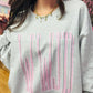 Gray sweatshirt with pink text worn by a person, with a colorful background.