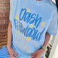 Person wearing a light blue t-shirt with 'Dash Forward' text and stars, standing against a brick wall.