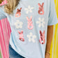 Person wearing a light blue t-shirt with rose gold peep bunny and white puff vinyl flower designs against a colorful striped background.