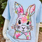 Light blue t-shirt with a floral bunny design on the back, worn by a person outdoors.